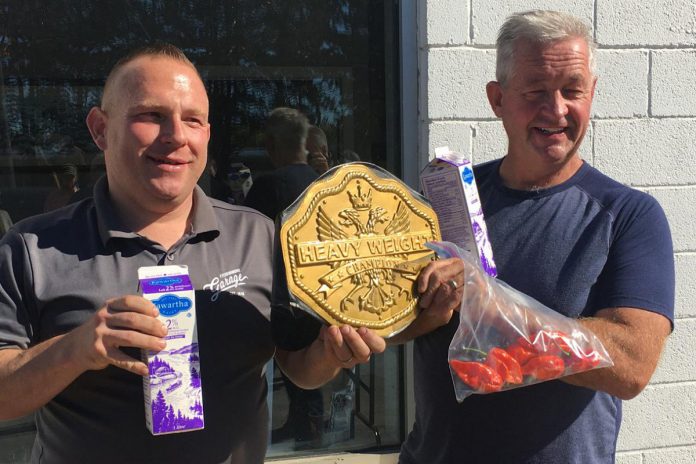 Mark Smith, operations manager of Fitzsimmons Towing and Repair in Peterborough, and retired Peterborough OPP constable Dave McNabb share the title after eating a ghost pepper in a fundraising event on October 19, 2021 for One City Peterborough. McNab holds a bag of ghost peppers grown in his home garden by his wife, veterinarian Kristy Hiltz. (Photo: Paul Rellinger / kawarthaNOW)