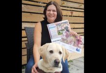 Leslie Yee, chair of the Canadian Council of the Blind's Peterborough chapter, with her guide dog Akira, displays the organization's 2022 fundraising calendar featuring cover art by Peterborough artist Lynda Todd. (Supplied photo)