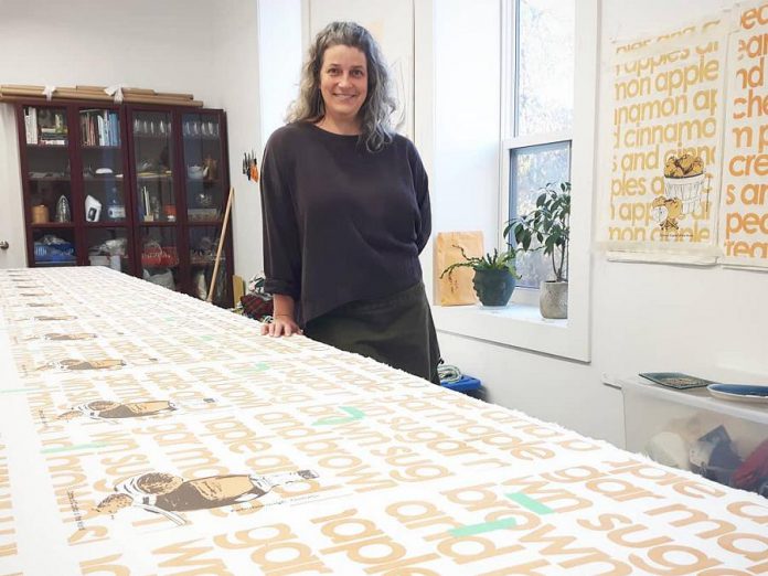 Madderhouse Textile Studio's 'breezy garb' tops are constructed with support from the Newcomer Sewing Crew, a social enterprise of female artists and sewists who are recent immigrants to Canada. Here Madderhouse owner Leslie Menagh poses with the Newcomer Sewing Group's first project, "The Oatmeal Capitol of the World" tea towels that were sold at Watson & Lou, which owns the space where Madderhouse is located. (Photo courtesy of Madderhouse Textile Studios)