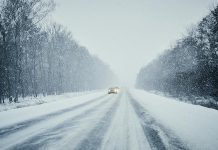 Cars on a snow-covered road during a winter storm. (Stock photo)