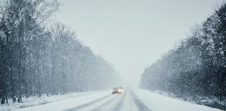 Cars on a snow-covered road during a winter storm. (Stock photo)