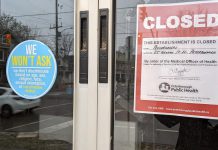 A notice in the window of Peterburgers at 25 George Street North in Peterborough that the restaurant has been closed by order of the medical officer of health, beside a decal posted by the restaurant stating that it does not ask for proof of vaccination, a requirement under the province's Reopening Ontario Act. (Photo: kawarthaNOW)