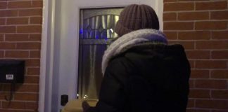 A screenshot from a video of a woman knocking on the door of the private residence of Peterborough medical officer of health Dr. Thomas Piggott on the evening of January 19, 2022. Inside the plastic food dish she is carrying is a piece of paper that, among other things, states the COVID-19 virus doesn't exist. Dr. Piggott closed the door before she could "serve" him the piece of paper. The woman, along with the man recording the video, was later arrested and charged with criminal harassment and intimidation of a health official. (kawarthaNOW screenshot)