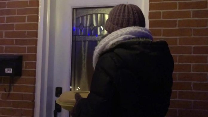 A screenshot from a video of a woman knocking on the door of the private residence of Peterborough medical officer of health Dr. Thomas Piggott on the evening of January 19, 2022. Inside the plastic food dish she is carrying is a piece of paper that, among other things, states the COVID-19 virus doesn't exist. Dr. Piggott closed the door before she could "serve" him the piece of paper. The woman, along with the man recording the video, was later arrested and charged with criminal harassment and intimidation of a health official. (kawarthaNOW screenshot)