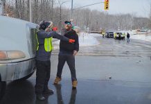 A convoy participant slaps away the hand of a counter-protester who was blocking a dump truck from proceeding through the intersection at Brealey Drive and Stenson Boulevard in Peterborough on February 19, 2022. The counter-protester was arrested and charged under the criminal code with intimidation for blocking the highway, and the convoy participant was arrested and charged with assault. (kawarthaNOW screenshot)