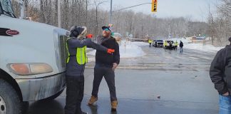 A convoy participant slaps away the hand of a counter-protester who was blocking a dump truck from proceeding through the intersection at Brealey Drive and Stenson Boulevard in Peterborough on February 19, 2022. The counter-protester was arrested and charged under the criminal code with intimidation for blocking the highway, and the convoy participant was arrested and charged with assault. (kawarthaNOW screenshot)
