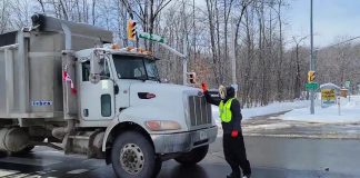 A counter-protester against the "slow roll" vehicle convoy in Peterborough on February 19, 2022, was pushed into the intersection of Brealey Drive and Stenson Boulevard after standing in the crosswalk attempting to block vehicles from going through the green light. Shortly after, a convoy participant potentially assaulted the counter protester. (kawarthaNOW screenshot)