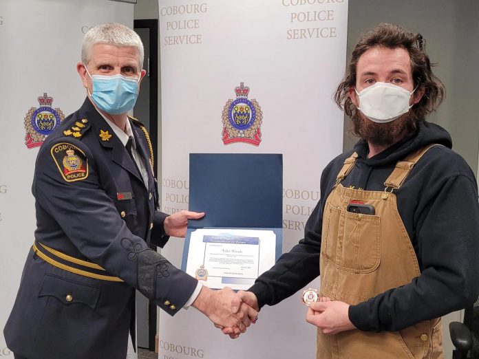 Tyler Woods receiving a certificate of appreciation and a Chief's Challenge Coin from Cobourg police chief Paul VandeGraaf. In January, Woods used his snowplow to block a suspect's escape route, allowing police to make an arrest.  (Photo: Cobourg Police Service)