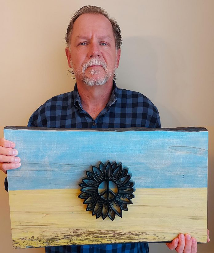 Peterborough artist Nick Leniuk with his piece "Overcome" which he auctions off to fund humanitarian efforts in Ukraine.  Leniuk was born in Kapuskasing, Ontario, where his father settled after immigrating to Canada from Ukraine after World War II.  (Photo courtesy of Nick Leniuk)