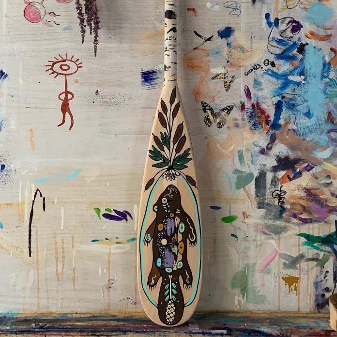 Cree artist Tara-Nuin Wilson (Star Daughter Woman) painted this paddle featuring the amik (beaver), with cattails, lillies, and pondweed and a handle inspired by aspen trees. (Photo courtesy of Peterborough DBIA)