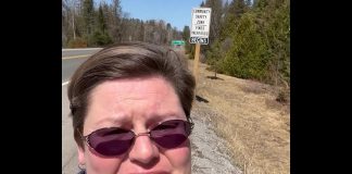 North Kawartha Carolyn Amyotte stands beside one of the signs indicating new "community safety zones" along Highway 28 where fines for certain driving infractions are doubled. One zone covers 3.5 kilometres of the highway as it passes through Apsley and the other zone covers 5.8 kilometres of the highway from Haultain through Woodview. (kawarthaNOW screenshot of Facebook video)