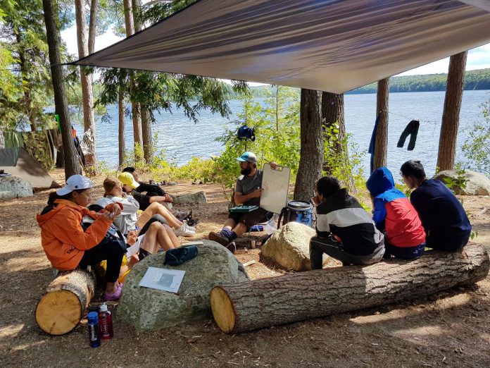 The Land Canadian Adventures' co-founder Bretton Clark, who is also an English as a second language (ESL) instructors, leads a group of Learning Languages in the Outdoors students in a lakeside language lesson at Algonquin Park.  (Photo courtesy of The Land Canadian Adventures)