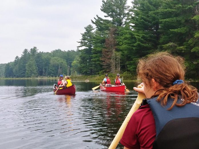 Young Trippers on their way to their campsite on Serpentine Lake in Kawartha Highlands Provincial Park after completing a challenging (but extremely rewarding) 1.5-kilometre portage from North Rathbun Lake.  (Photo courtesy of The Land Canadian Adventures)