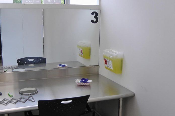 One of the three consumption booths at the Consumption and Treatment Services site (CTS), located at the Opioid Response Hub at 220 Simcoe Street in downtown Peterborough. Each booth has a mirror so the on-site paramedic can observe people as they prepare and consume their substances, as well as biohazard bin where the person can discard used equipment. (Photo: Bruce Head / kawarthaNOW)