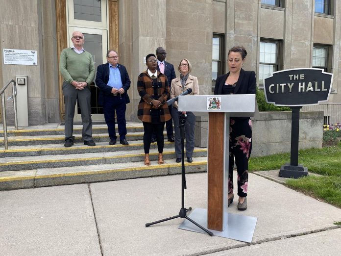 Mayor Diane Therrien delivers a statement on behalf of Peterborough city council outside city hall on May 17, 2022, in which she condemned the behaviour of protestors during federal NDP leader Jagmeet Singh's visit to Peterborough the previoius week. Also pictured are city councillors Henry Clarke, Keith Riel, Kemi Akapo, Stephen Wright, and Kim Zippel. (Photo: Paul Rellinger / kawarthaNOW)