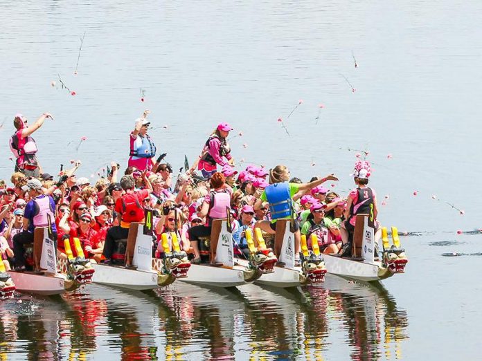 Paddlers at the 2015 Peterborough's Dragon Boat Festival toss flowers into Little Lake, an annual tradition to both remember and honour those who have lost their battle with breast cancer. (Photo: Linda McIlwain / kawarthaNOW)