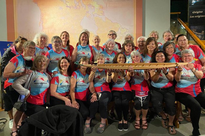 Members of Dragons Abreast, the first breast cancer survivor dragon boat team in Toronto and one of the first in the world, with the five-foot model of a dragon boat they donated to The Canadian Canoe Museum in Peterborough on June 15, 2022. The model is a scale replica of the dragon boat built in 2008 by the Avalon Dragons, Newfoundland and Labrador's first breast cancer survivor dragon boat team. (Photo: The Canadian Canoe Museum / Facebook)