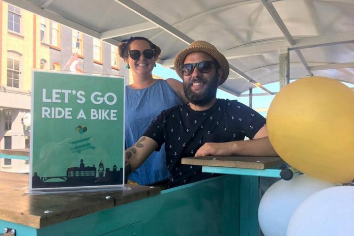 PedalBoro owners and operators Hillary Flood and Pete Rellinger at the 2019 launch of the 15-passenger party bike at the centre of their new business venture. Offering downtown tours in partnership with local pubs and eateries, PedalBoro offers an eco-friendly transportation alternative for exploring Peterborough's core. (Photo: Paul Rellinger / kawarthaNOW)