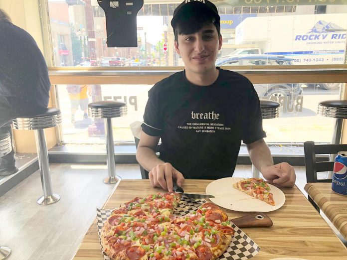 Rashid enjoys a slice of pizza for the very first time at Brothers Pizza in downtown Peterborough. Shortly after leaving the Toronto airport, Rashid and his sponsors stopped for some poutine (another first for Rashid) and sang O Canada in honour of Rashid's arrival in his new home. (Photo courtesy of Dave McNab)