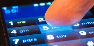 A finger dials a number on a smartphone's touchscreen. (Stock photo)