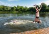 Two girls jumping off a dock into a lake during the summer. (Stock photo)