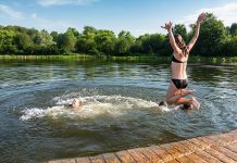 Two girls jumping off a dock into a lake during the summer. (Stock photo)