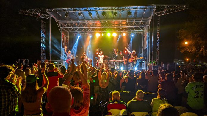 The Strumbellas (lead guitarist Jon Hembrey, violinist Isabel Ritchie, lead vocalist Jimmy Chauveau, drummer Jeremy Drury, keyboardist David Ritter, and bassist Darryl James) performed in Del Crary Park at Peterborough Musicfest on August 10, 2022. (Photo: Bruce Head / kawarthaNOW)