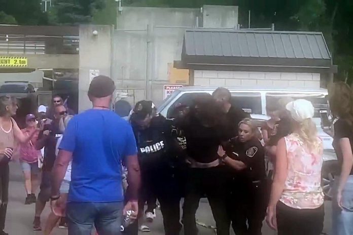 While other protesters watch, police arrest a man during an incident at the Peterborough police station on August 13, 2022. (kawarthaNOW screenshot of Twitter video)