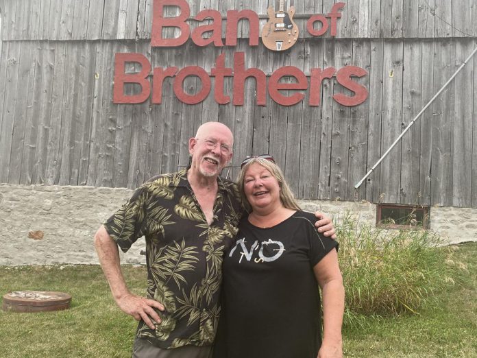 Andy and Linda Tough pose outside their Norwood area barn that has doubled as a recording studio for a number of years, not only allowing them to host live music jams on a regular basis but also record and produce live off-the-floor performances by a number of artists for 18 episodes of Live! At The Barn which were aired on Tough’s YouTube channel. The Toughs, whose property is up for sale, hosted one last jam on August 7, 2022. (Photo: Paul Rellinger / kawarthaNOW)