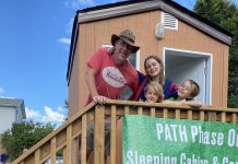 Peterborough teacher Aaron McFadden with his children at the prototype "tiny home" for people experiencing homelessness. McFadden will be sleeping in the cabin on Rubidge Street opposite Cathedral of St. Peter-in-Chains overnight on September 3, 2022 to raise awareness and funds for the Peterborough Action for Tiny Homes (PATH), a grassroots initiative with the goal of creating a village of 50 tiny homes to help house some of the 317 people without a home in Peterborough. (Photo courtesy of PATH)