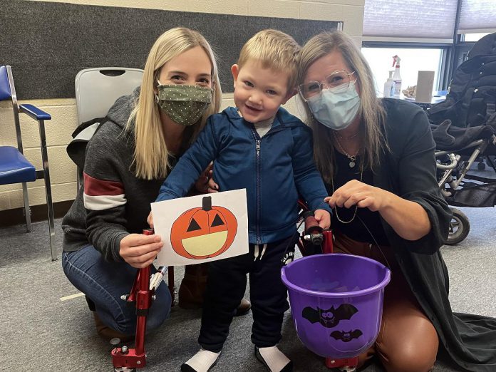 More than 400,000 children in Canada have special needs that may prevent them from enjoying trick-or-treating with their siblings and other children.  There are simple ways to make Halloween more accessible and inclusive for children of all ages and abilities, including two-year-old Xavier, pictured with his mother Jessica (left) and Ange, a staffer at the Five Counties Children's Center.  (Photo courtesy of Five Counties Children's Centre)