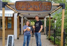 The Canadian Canoe Museum executive director Carolyn Hyslop and Silver Bean Cafe owner Dan Brandsma celebrate their new partnership by donning each other's t-shirts and raising a cup of coffee to their future together. The Silver Bean Café on the Lake will operate seven days a week at the new Canadian Canoe Museum at 2077 Ashburnham Drive on the shores of Little Lake when the new museum opens in summer 2023. (Photo courtesy of The Canadian Canoe Museum)