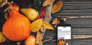 A mobile phone sitting on a harvest table covered with squash and fall leaves displaying kawarthaNOW's Thanksgiving holiday hours story. (kawarthaNOW photo)