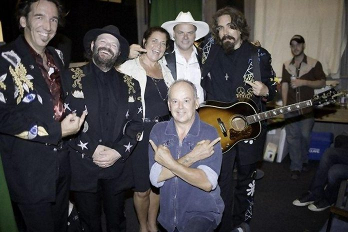 Blackie and the Rodeo Kings formed in 1996 to record a one-off tribute album for Peterborough singer-songwriter Willie P. Bennett (front). Pictured are Stephen Fearing, Colin Linden, kawarthaNOW's Jeannine Taylor, Fred Eaglesmith, and Tom Wilson at a July 27, 2007 benefit show at the Market Hall in Peterborough for Willie P., who had to stop touring after suffering a heart attack (he died six months after this photo was taken of a another heart attack). The middle fingers are in-joke known as the "Willie P. salute."  (Photo: Rainer Soegtrop)