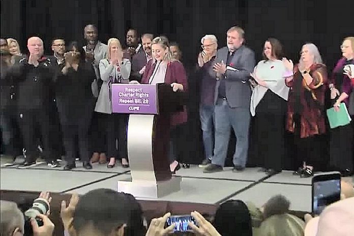 Labour leaders and representatives of public and private sector unions in Ontario and across Canada applaud after Laura Walton, president of the Ontario School Board Council of Unions (OSBCU) that represents education workers at the bargaining table, confirms at a media conference on November 7, 2022 that the provincial government will repeal its controversial Bill 28. (kawarthaNOW screenshot of CPAC video)