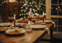 A dinner table set for a holiday celebration with a Christmas tree in the background. (Stock photo)