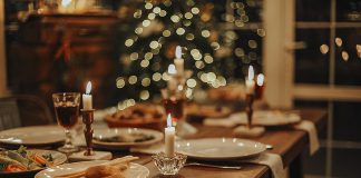 A dinner table set for a holiday celebration with a Christmas tree in the background. (Stock photo)