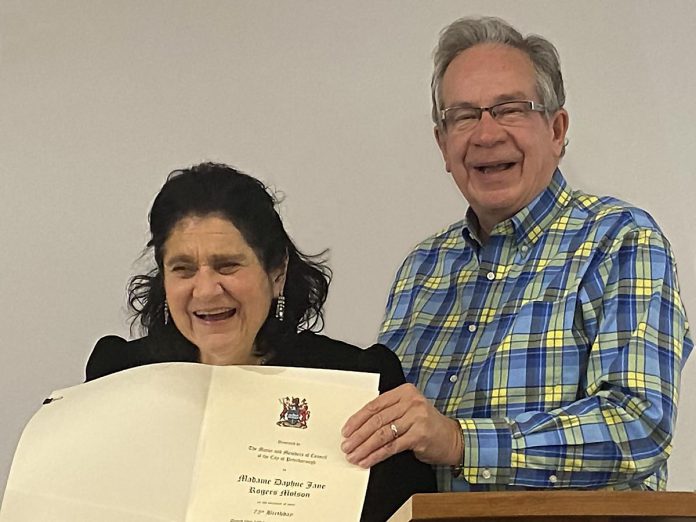 Peterborough mayor Jeff Leal (right) presents Madame Daphne Jane Rogers Molson with a citation recognizing the 75th birthday of the local poet, musician, and arts supporter at a celebration at the Peterborough Public Library on December 14, 2022. (Photo: Paul Rellinger / kawarthaNOW)