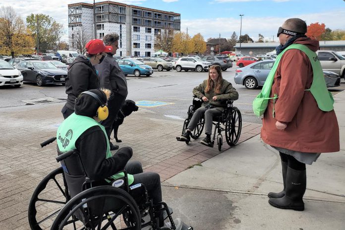 In a recent event in Peterborough's Market Plaza, GreenUP staff and the public were able to experience what it is like to transit around a parking lot using a wheelchair, ear-defenders, and goggles that block your sight, and understand the barriers that persons with disabilities face when in the natural and built environment. (Photo: Lili Paradi / GreenUP).