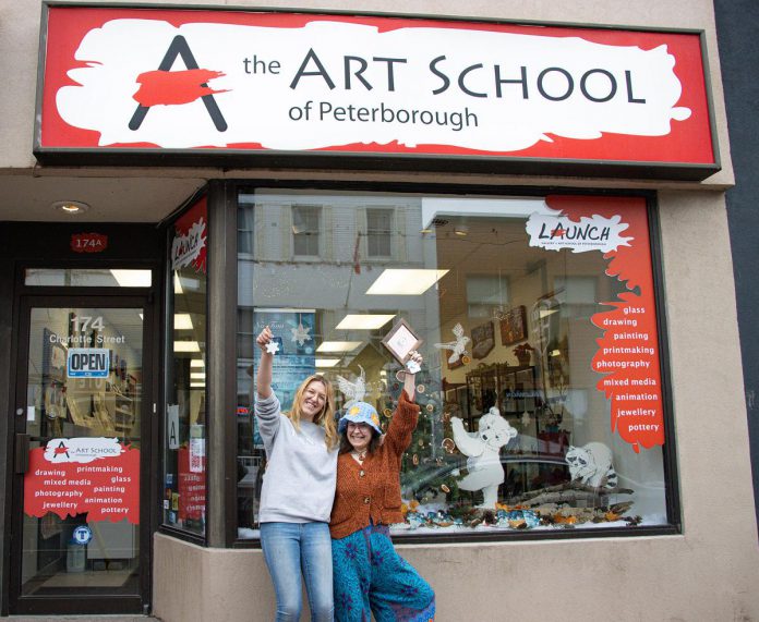 The Art School of Peterborough co-op student Cecilia Van Mierlo (left) and receptionist Raine Knudsen (right) hold up a snowflake ornament and first place award for their window display in the 2022 holiday window contest sponsored by the Peterborough Downtown Business Improvement Area (DBIA). As first-place winner, the school receives $1,000. Over 3,000 votes were cast online for 27 window displays at downtown businesses and organizations. (Photo courtesy of Peterborough DBIA)