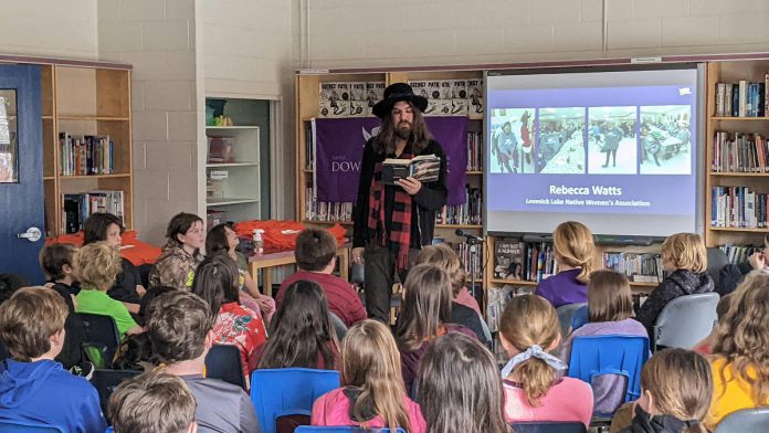 Hamilton-based musician, artist, and author Tom Wilson reads from his memoir "Beautiful Scars" during a December 8, 2022 event at Immaculate Conception Catholic Elementary School in Peterborough organized by the Gord Downie & Chanie Wenjack Fund in partnership with Sony Music Publishing. Wilson told the students about his discovery nine years ago, at the age of 54, that he was actually Indigenous. (Photo: Bruce Head / kawarthaNOW)