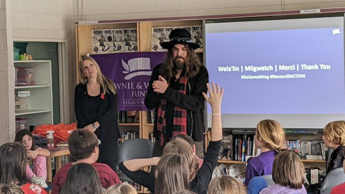 Hamilton-based musician, artist, and author Tom Wilson listens to a question from a student during a December 8, 2022 event at Immaculate Conception Catholic Elementary School in Peterborough, while Lisa Prinn of the the Gord Downie & Chanie Wenjack Fund looks on. (Photo: Bruce Head / kawarthaNOW)