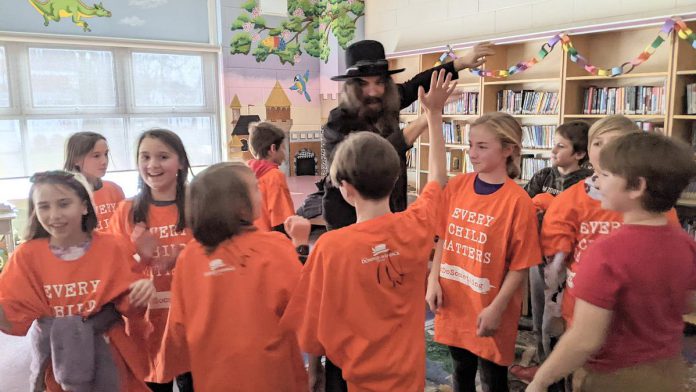 Hamilton-based musician, artist, and author Tom Wilson gives high-fives to students during a December 8, 2022 event at Immaculate Conception Catholic Elementary School in Peterborough.   (Photo: Bruce Head / kawarthaNOW)