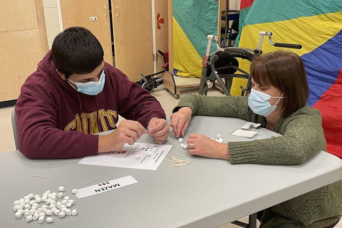 Five Counties Children's Centre recreation therapist Colleen Ristok (right) assists a client during a recent robotic Lego building event. The session gave participants a hands-on opportunity to build with various materials, including marshmallows and later robotic Lego. (Photo courtesy of Five Counties Children's Centre)