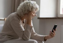 An older woman in distress looking at her mobile phone. (Stock photo)
