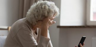 An older woman in distress looking at her mobile phone. (Stock photo)