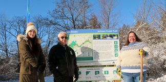 Eliza Braden-Taylor, Chief Keith Knott, and Anne Taylor of Curve Lake First Nation at a new Jackson Creek Trail trailhead sign during an event on January 14, 2023 to celebrate the the completion of Ontonabee Conservation's Jackson Creek Trail revitalization project. Curve Lake First Nation Cultural Centre helped develop the educational signs that were part of the project, which also included installing new trailhead signs and benches, fixing erosion along the trail, installing culverts, regrading slopes, enhancing bridges and railings, and resurfacing the length of the trail. (Photo courtesy of Otonabee Conservation)