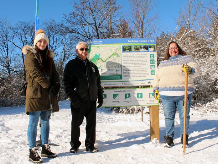 Eliza Braden-Taylor, Chief Keith Knott, and Anne Taylor of Curve Lake First Nation at a new Jackson Creek Trail trailhead sign during an event on January 14, 2023 to celebrate the the completion of Ontonabee Conservation's Jackson Creek Trail revitalization project. Curve Lake First Nation Cultural Centre helped develop the educational signs that were part of the project, which also included installing new trailhead signs and benches, fixing erosion along the trail, installing culverts, regrading slopes, enhancing bridges and railings, and resurfacing the length of the trail. (Photo courtesy of Otonabee Conservation)