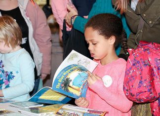 A young reader explores a book during a previous Peterborough Family Literacy Day event at Peterborough Square. After a two-year absence because of the pandemic, the annual event returns for the morning of Saturday, January 28, 2023. (Photo courtesy of Peter Rellinger)