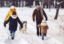 A family of four with a dog walking in winter snow. (Stock photo)
